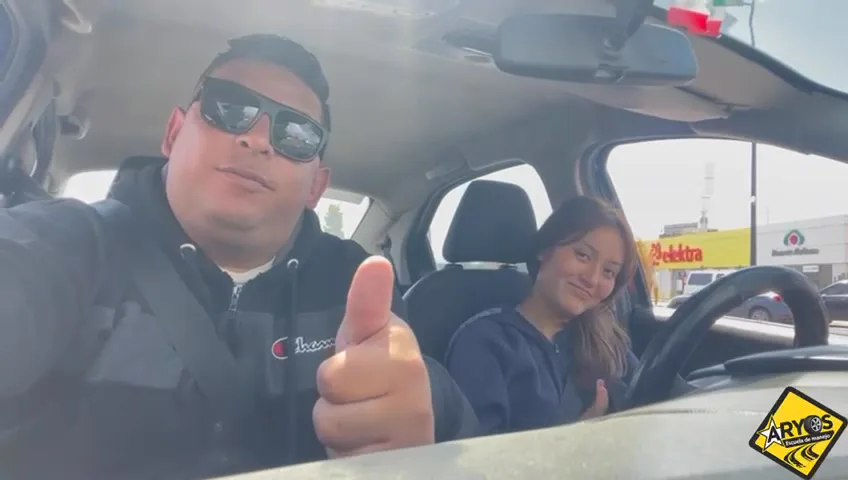 Instructor con el pulgar arriba y alumna al volante
