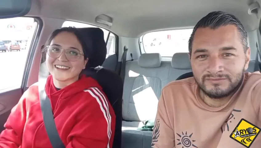 Alumna e instructor sonriendo dentro del auto durante una clase de manejo